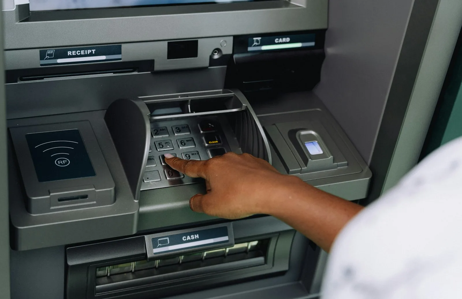 Person typing a PIN at an ATM