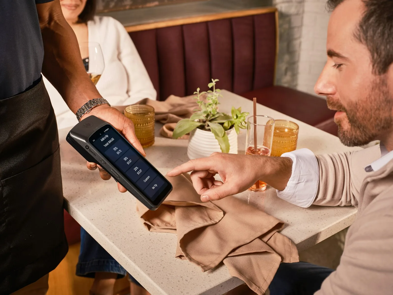 Customer paying on the card machine the waiter brought to the table