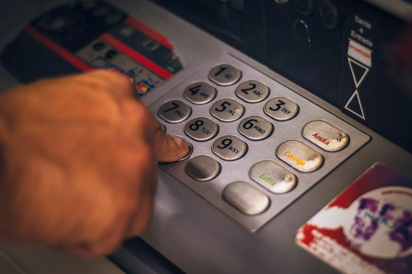 Hand typing a PIN on an ATM keypad