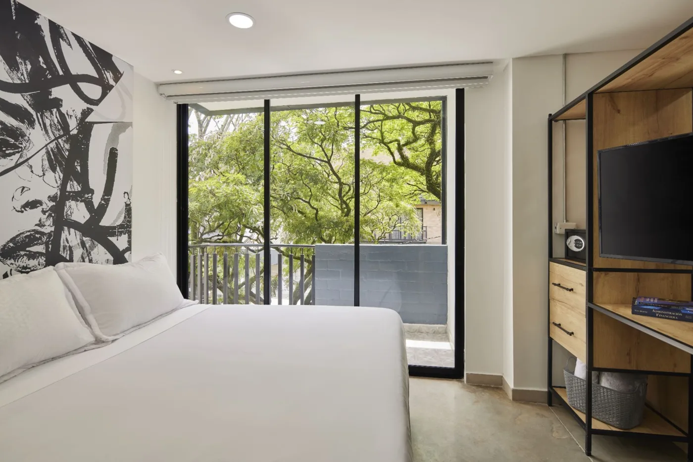 Suite Balcón con cama, mural en blanco y negro y puerta al balcón entre árboles