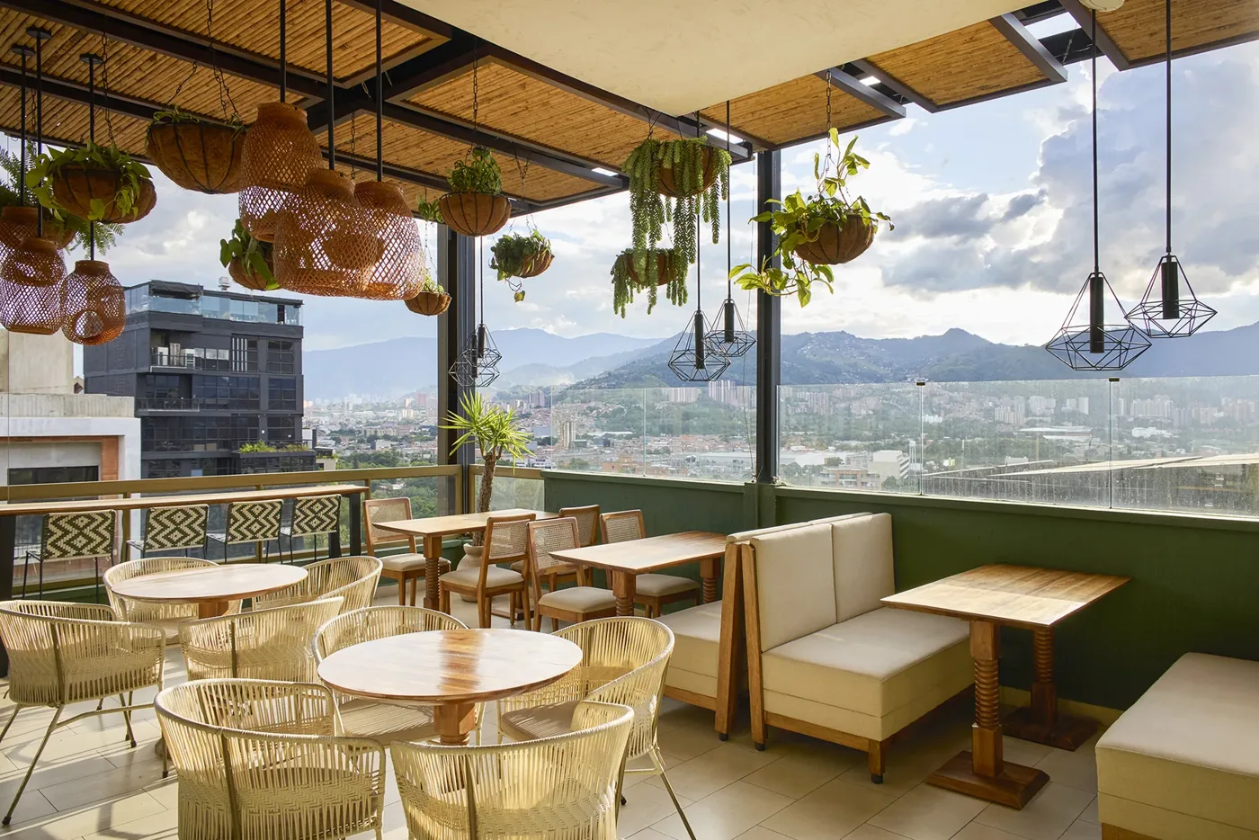 Rooftop de Golden Valley con lámparas de mimbre, mesas y vista a las montañas de Medellín