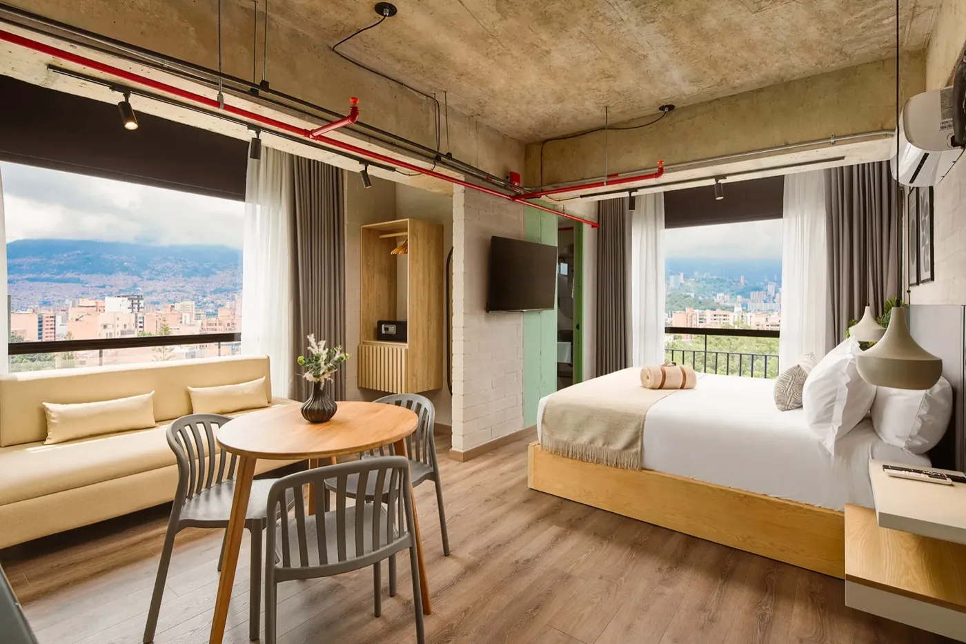 Suite de Lujo con sofá, comedor, cama y ventanales con vista a Medellín