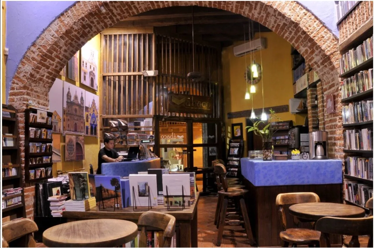 Entrada en arco de ladrillo de Ábaco Libros y Café con mesas y libros