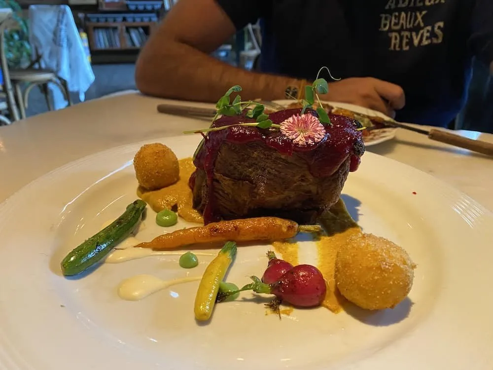 Plato de carne con zanahorias, rábanos y croquetas en Alambique