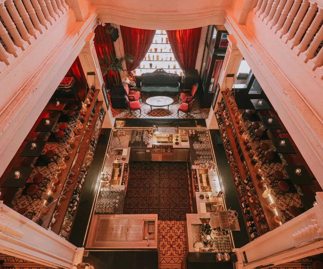 Interior de la casona de Alquímico visto desde lo alto, con cortinas rojas