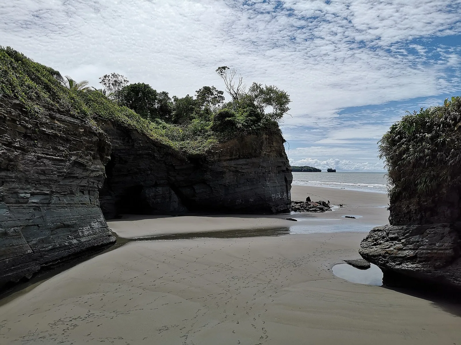 Playa de arena oscura entre acantilados en Ladrilleros, Parque Uramba Bahía Málaga