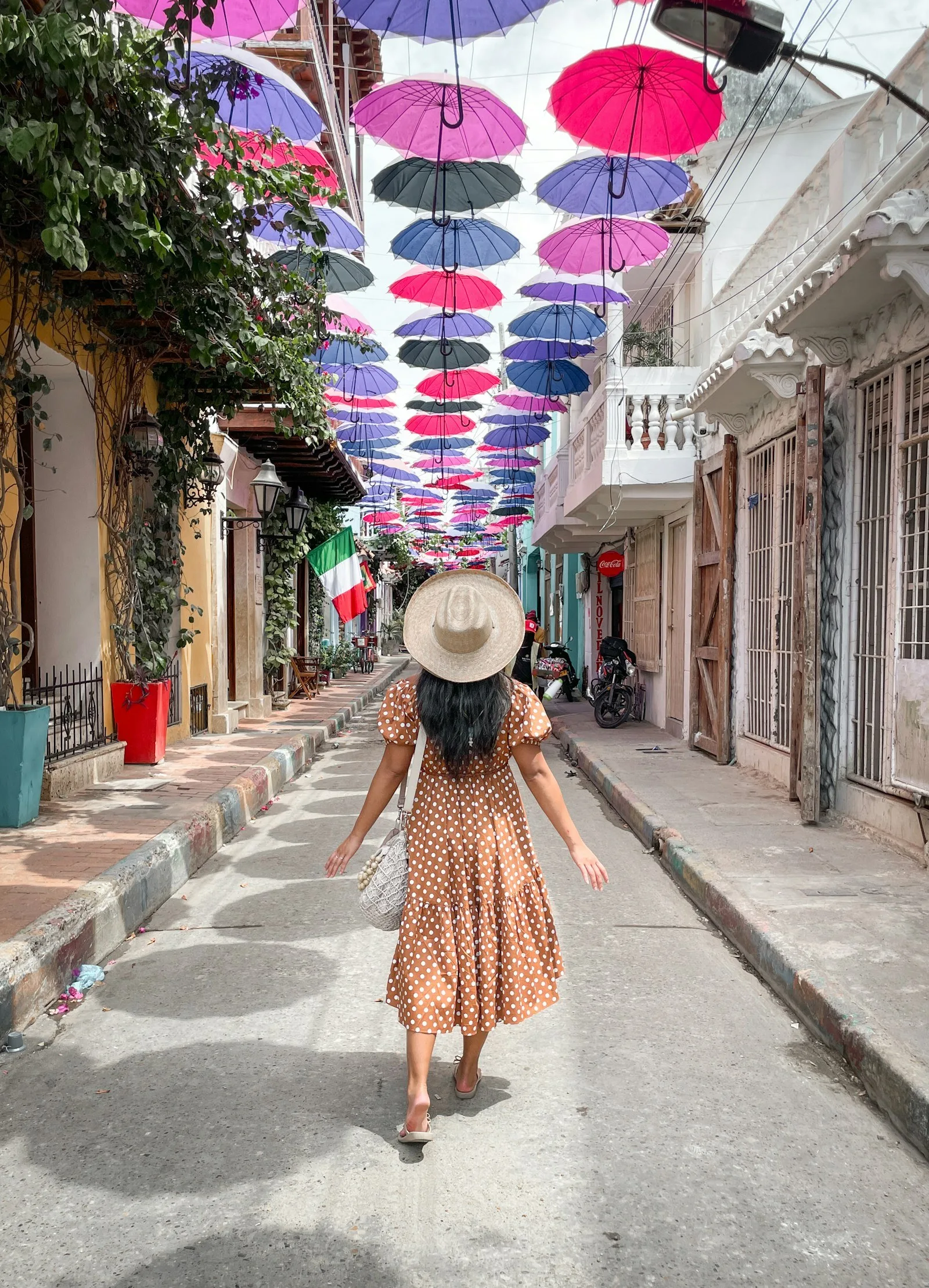 Una viajera con sombrero camina por la calle de las sombrillas en Getsemaní