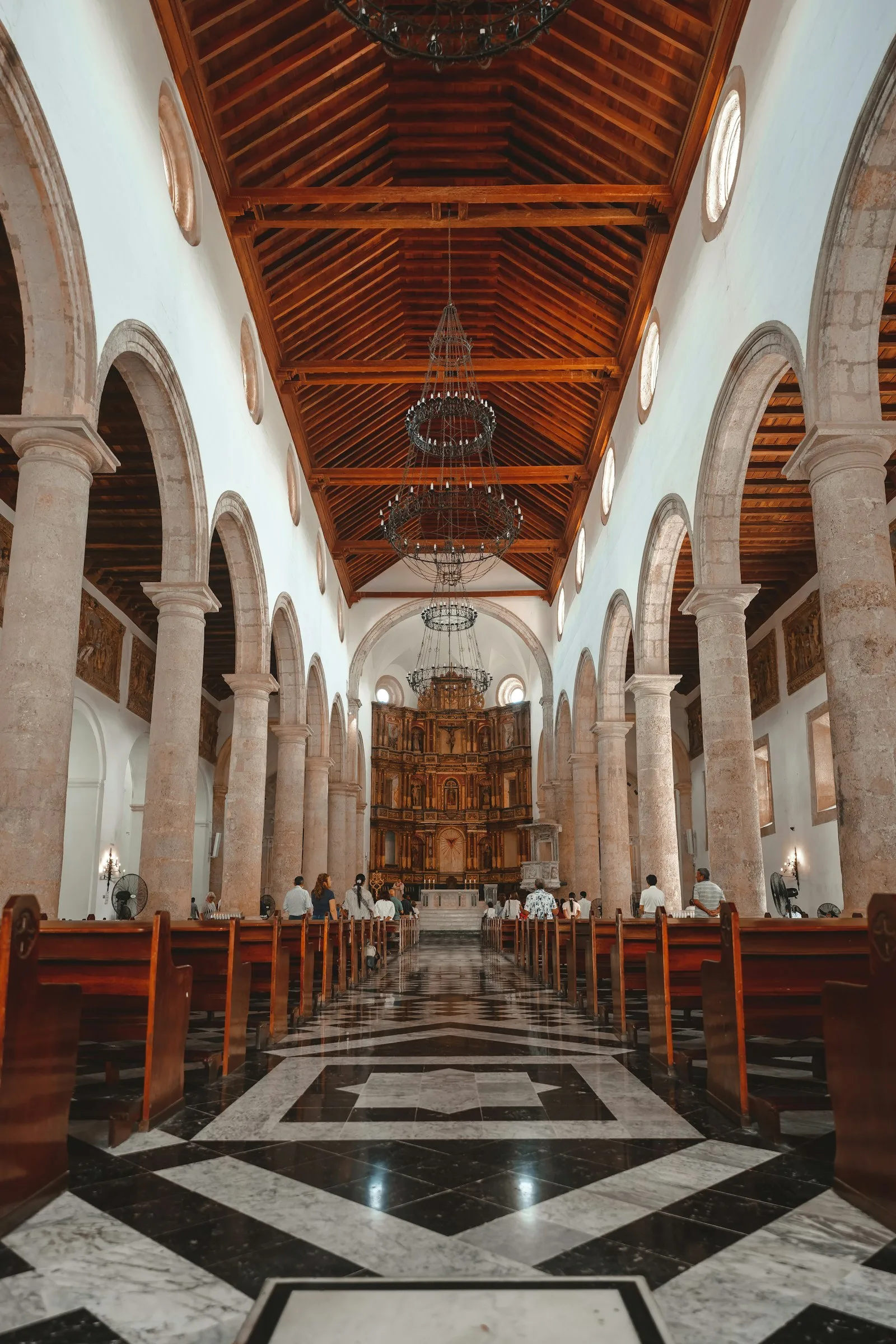 Nave central de la catedral con arcos, techo de madera y piso de mármol