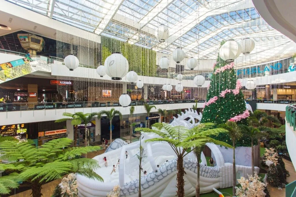 Plazoleta interior de El Tesoro bajo su cubierta de vidrio, con helechos y locales en varios niveles