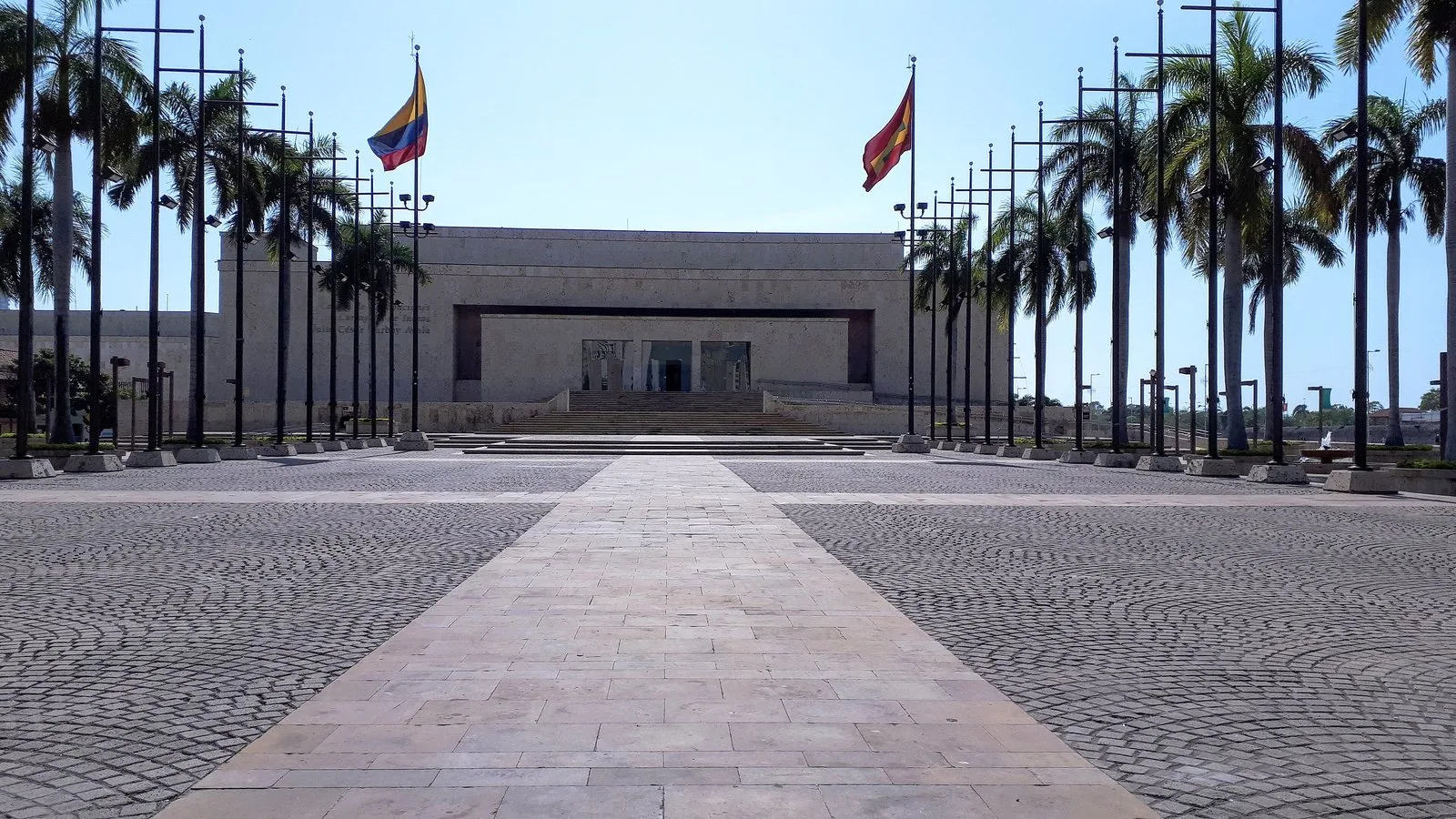 Plaza de entrada del Centro de Convenciones, con astas de bandera y palmeras a lado y lado
