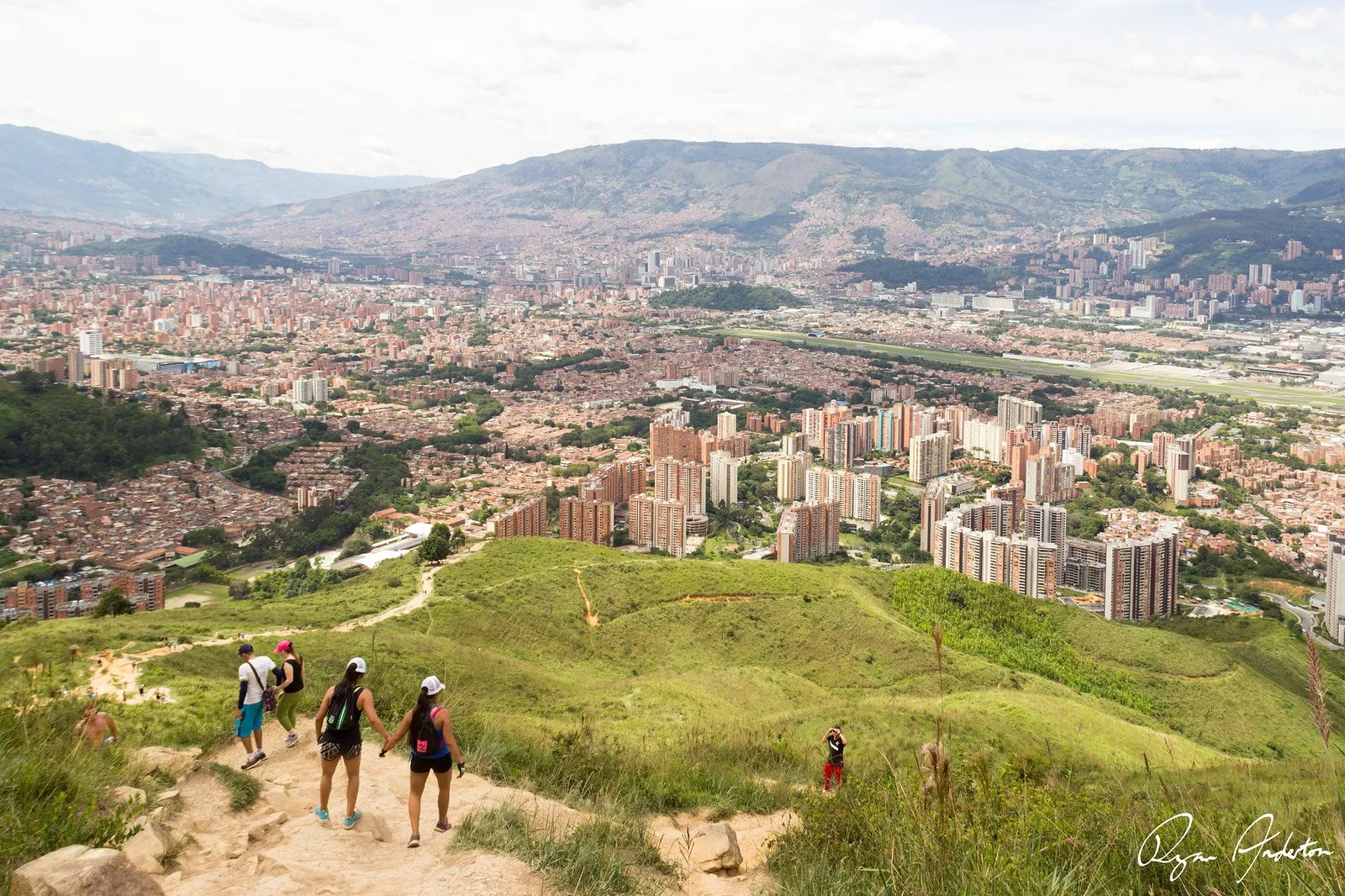 Caminantes bajando por el sendero del Cerro de las Tres Cruces con Medellín al fondo