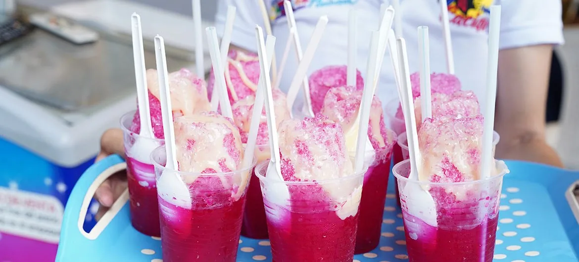 Bandeja de raspados con melado y leche condensada en un puesto de cholado