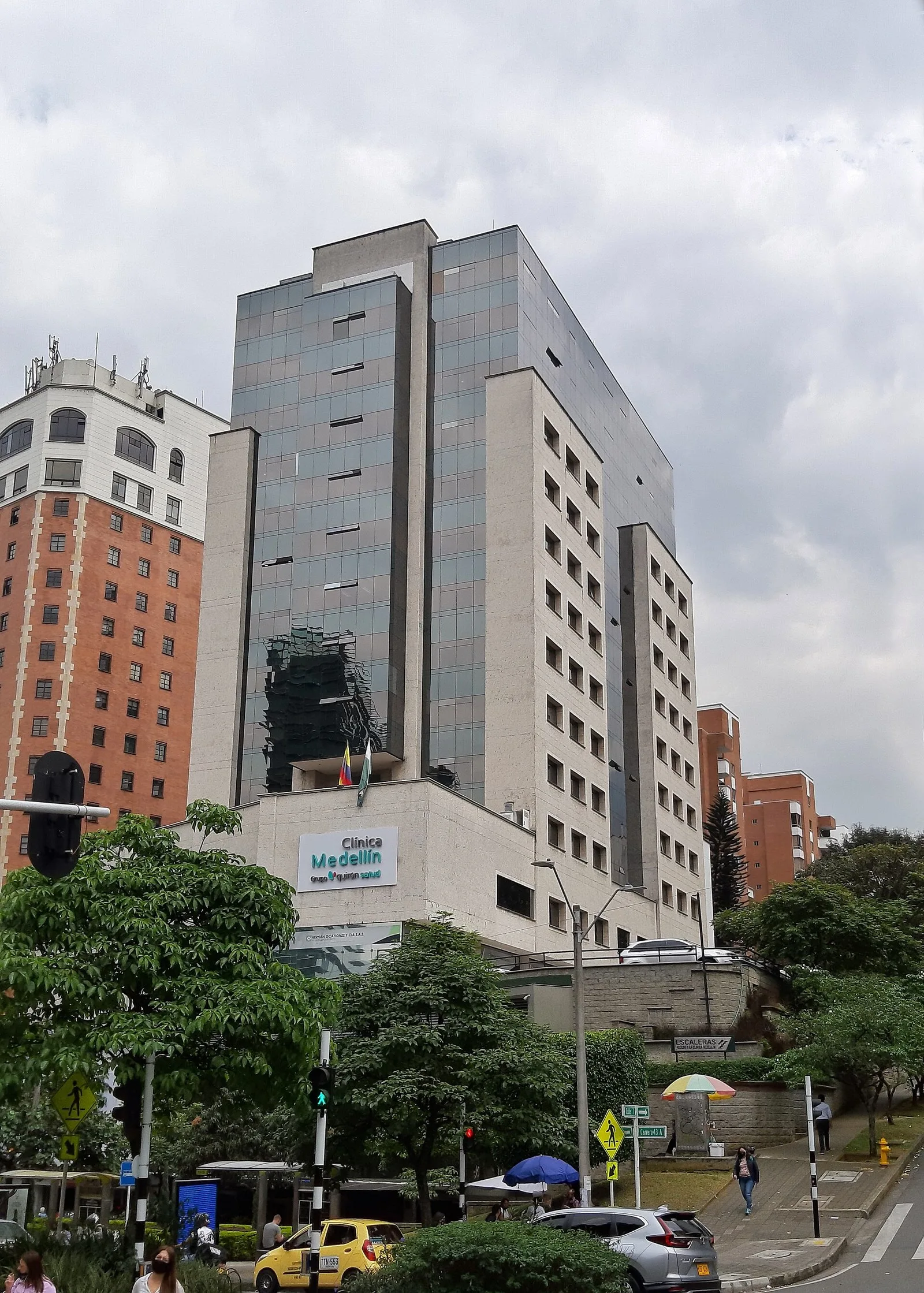 Clínica Medellín sede El Poblado vista desde la avenida, entre árboles