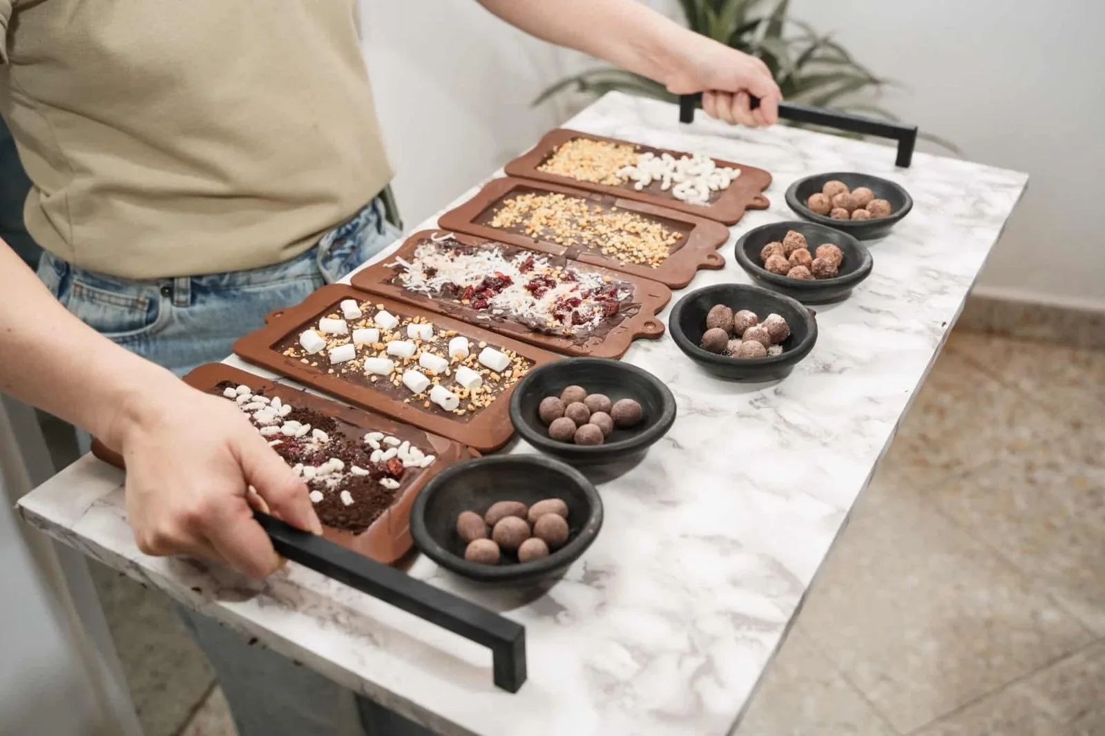 Bandeja de mármol con barras de chocolate con toppings y bombones en cuencos negros