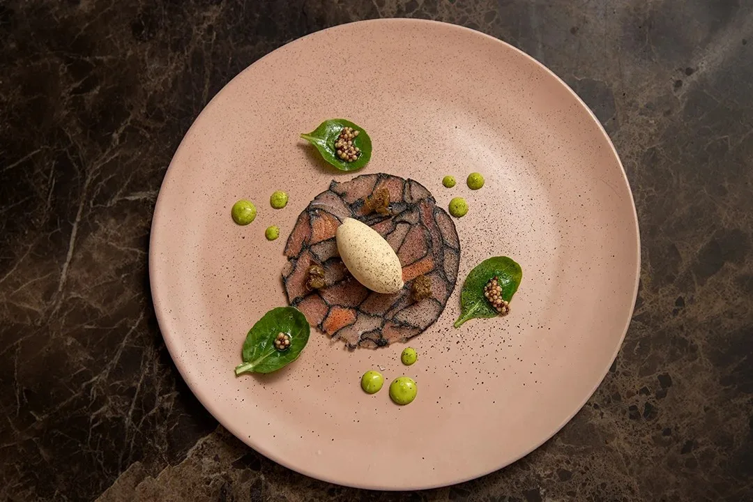 Plato de The Journey en El Cielo Medellín, carne en láminas con helado y hojas de espinaca