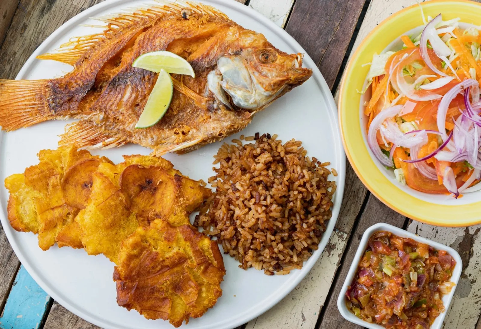 Pescado frito con patacones, arroz con coco y ensalada de cebolla en El Social