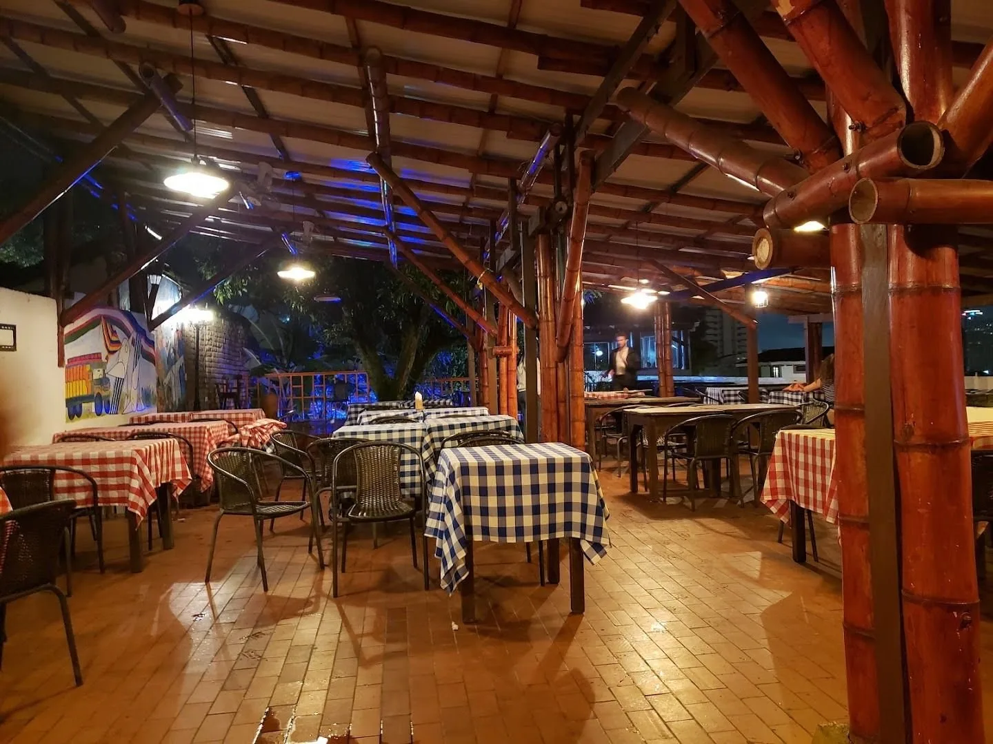Terraza del Zaguán de San Antonio de noche, con manteles de cuadros y techo de guadua