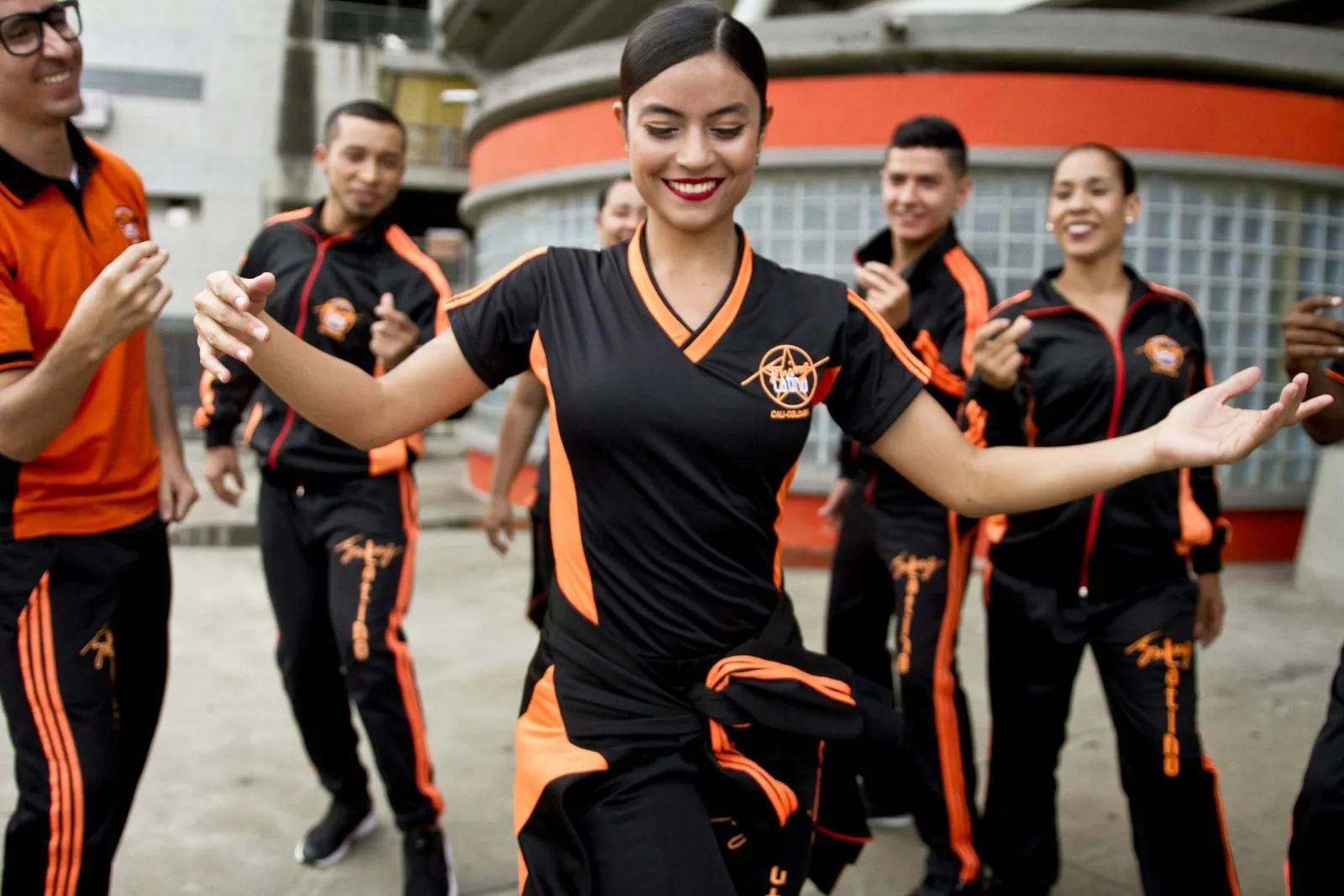 Grupo de Swing Latino bailando con uniforme negro y naranja