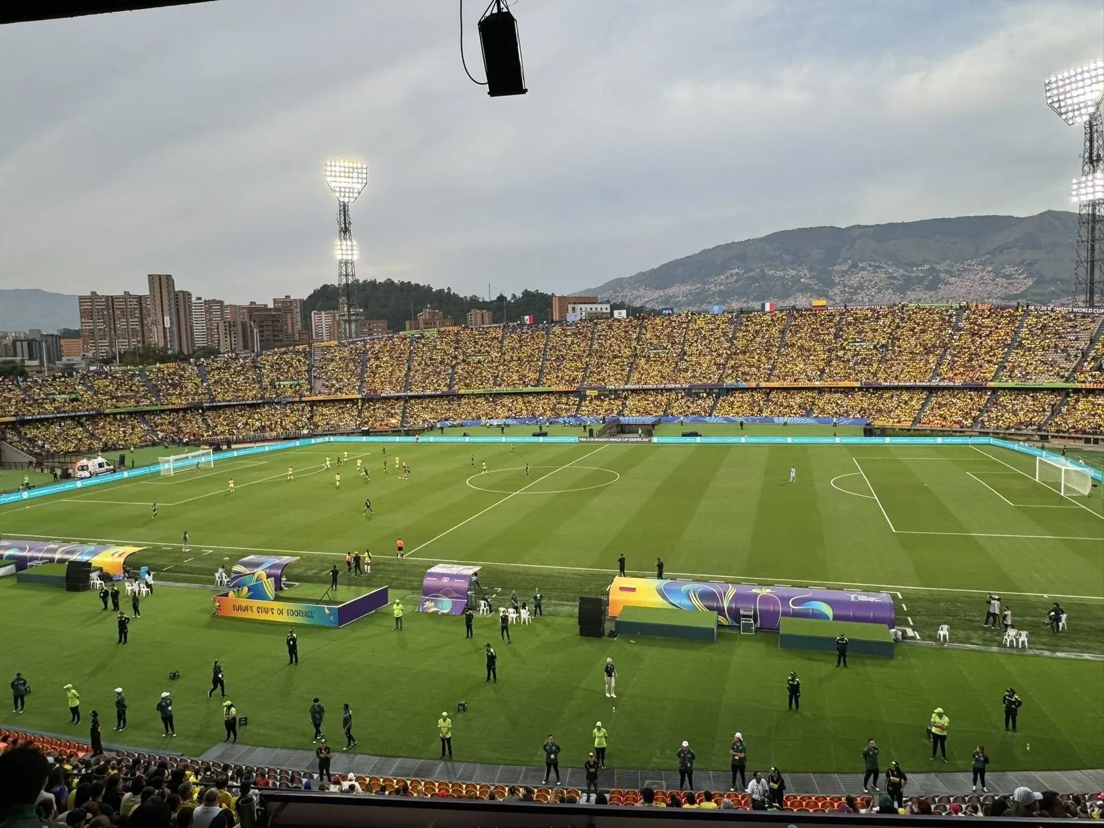 Tribunas llenas y cancha del Estadio Atanasio Girardot antes de un partido, con las montañas de Medellín al fondo