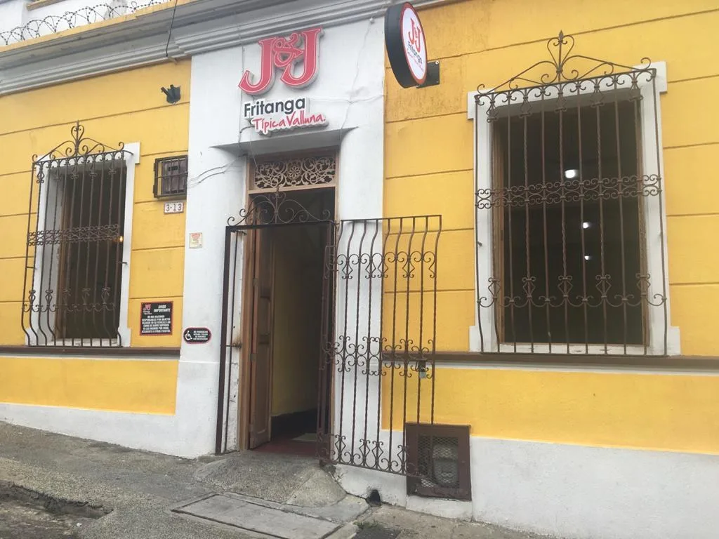 Fachada amarilla de Fritanga J&J en San Antonio, con rejas de hierro en las ventanas