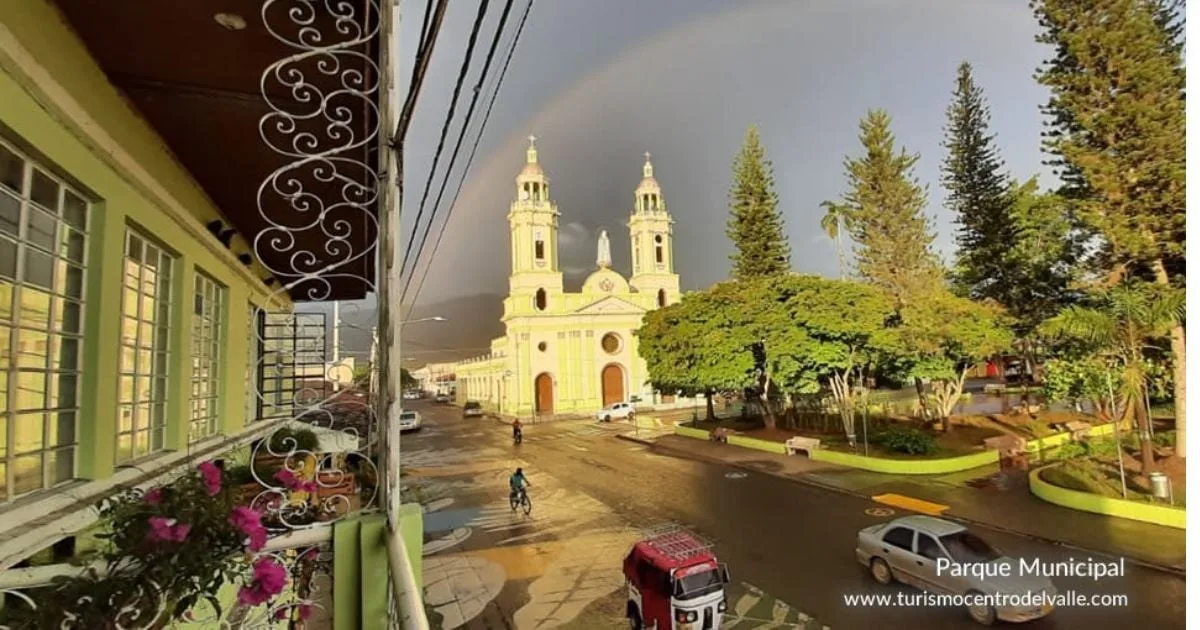 Parque principal de Ginebra con la iglesia de dos torres y un arcoíris