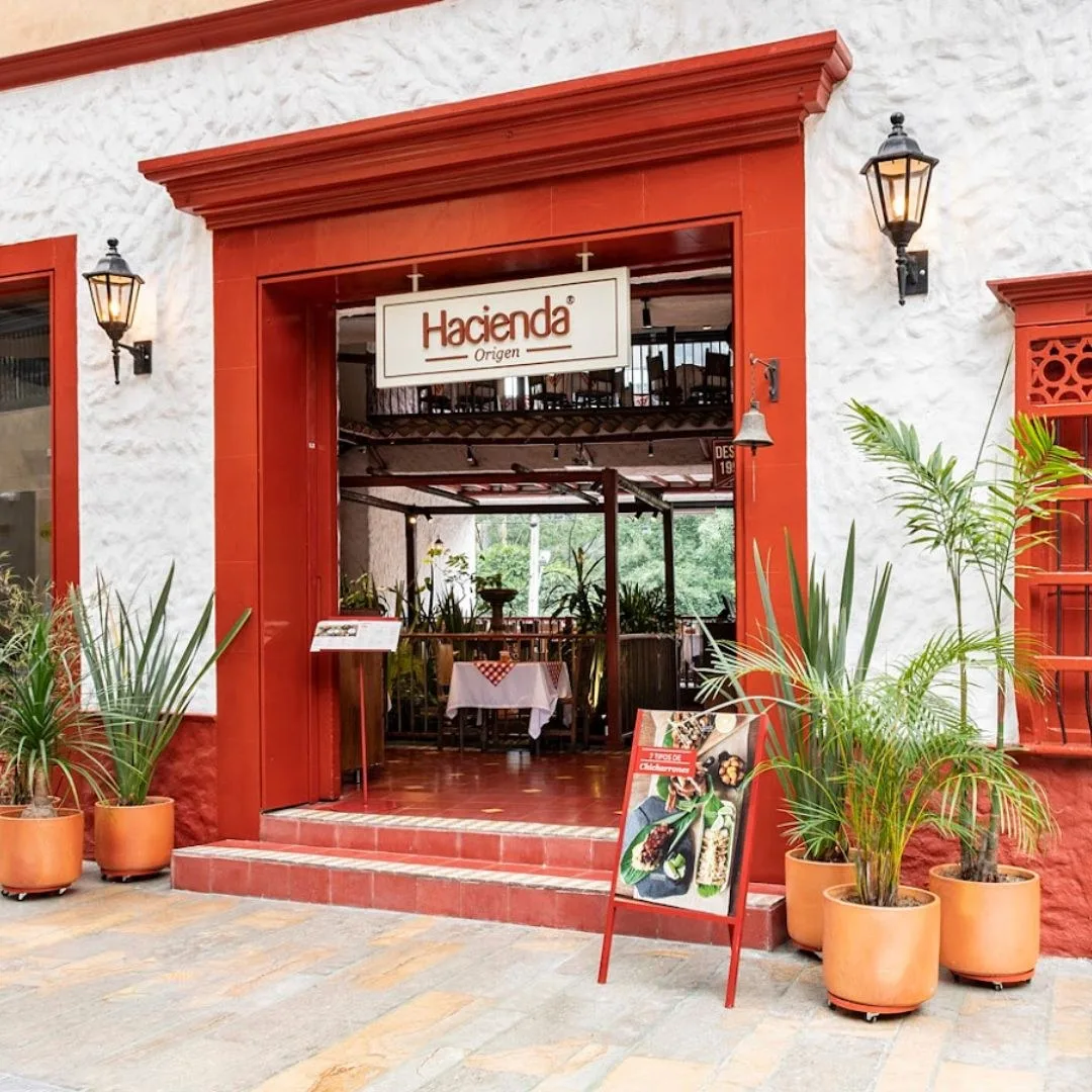 Entrada de Hacienda Origen con marco rojo, faroles y matas