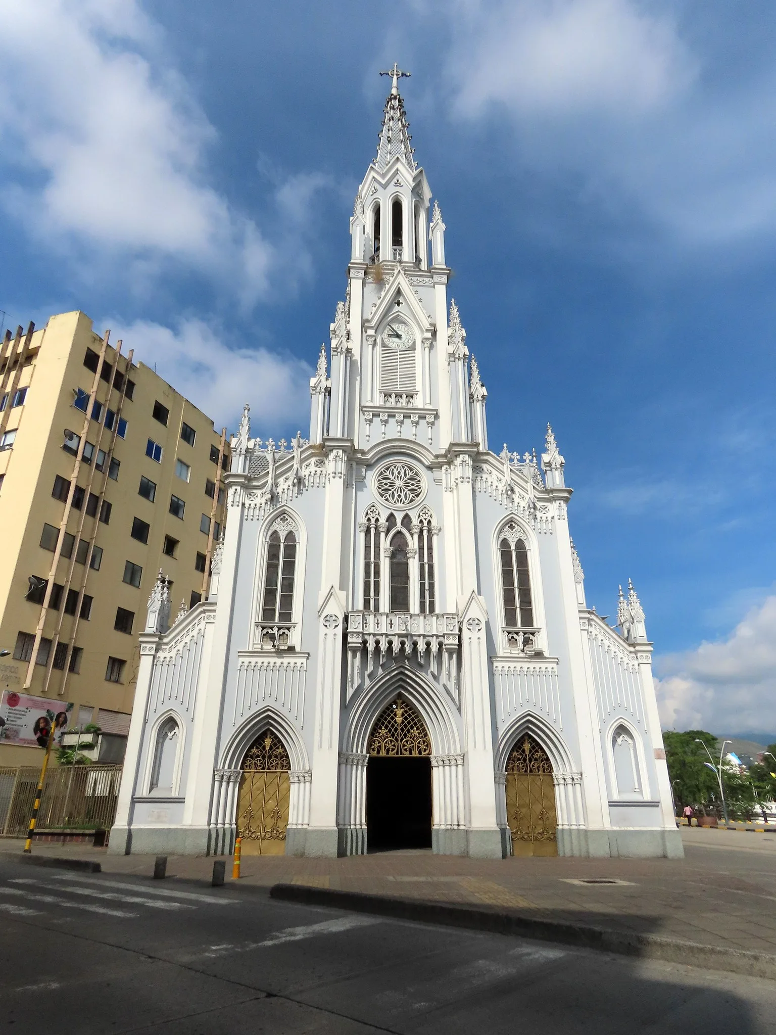 Fachada neogótica blanca de La Ermita bajo un cielo azul con nubes