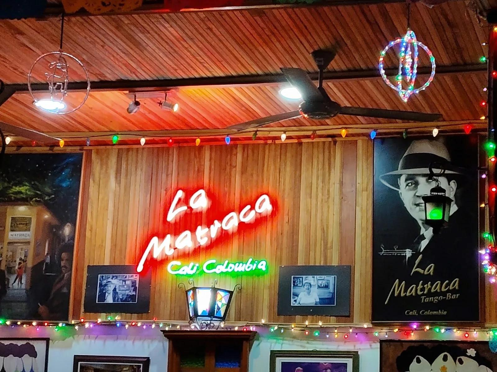 Letrero de neón de La Matraca entre retratos de cantantes de tango