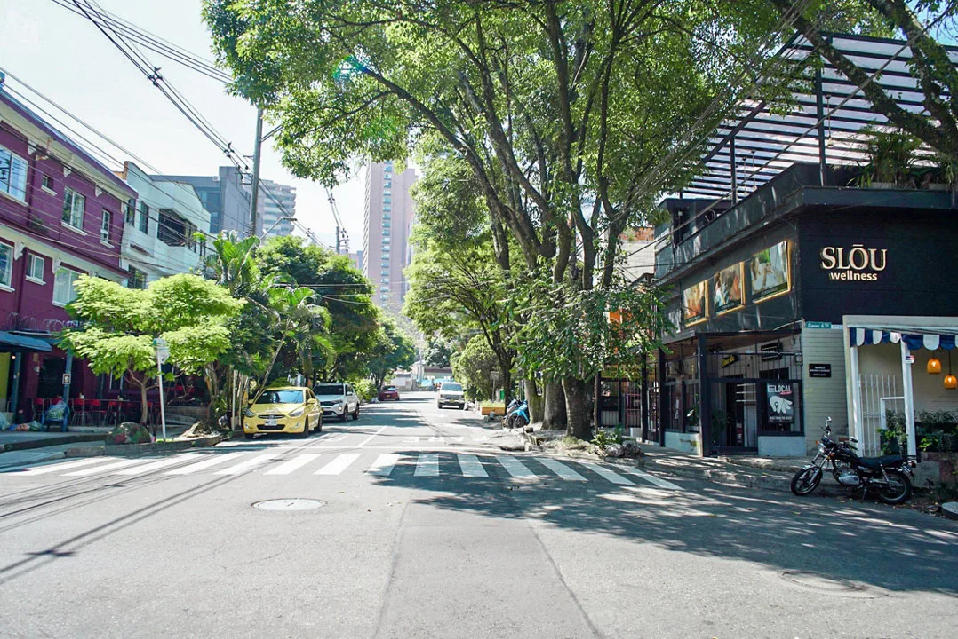 Calle de Manila con árboles grandes, casas de dos pisos y locales a nivel de calle