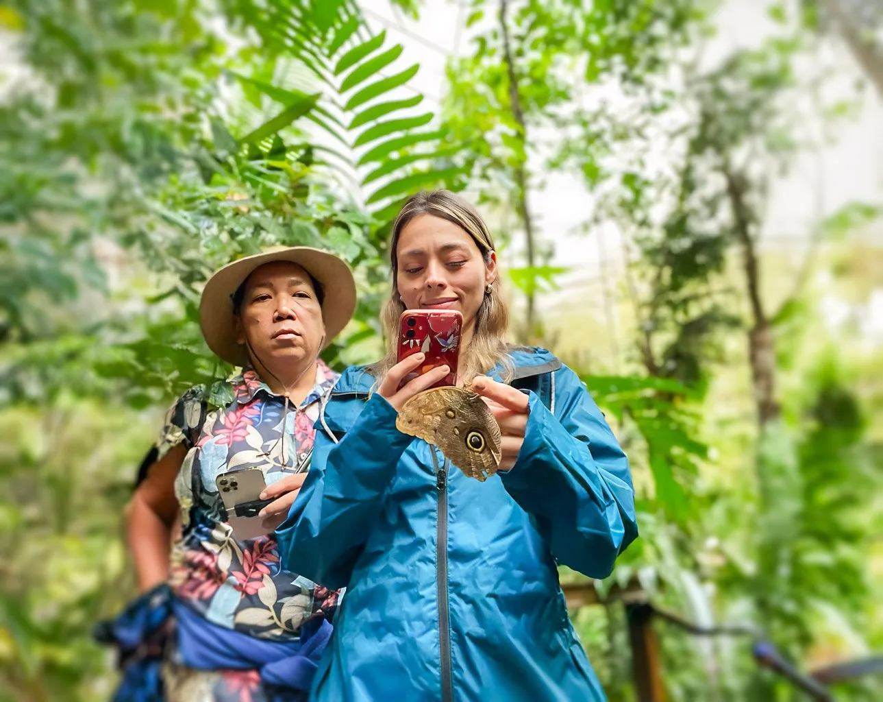 Visitantes fotografiando una mariposa posada en la mano durante el Paseo de las Mariposas