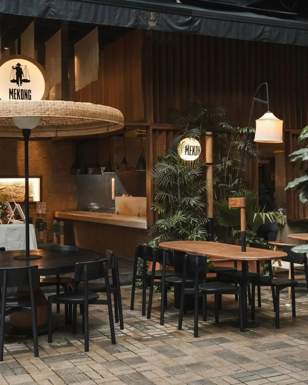 Terraza de Mekong en Laureles, con muros de madera, plantas y lámparas de papel