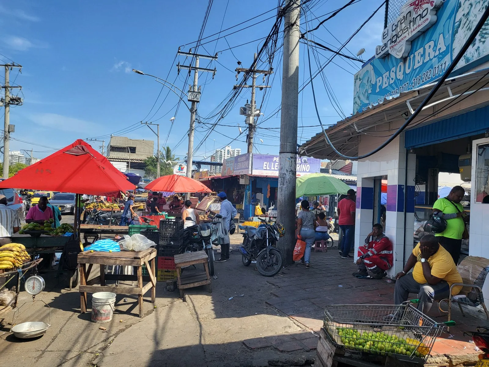 Puestos con toldos rojos y vendedores en el Mercado de Bazurto