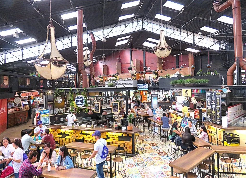 Interior de la bodega del Mercado del Río con puestos de comida y techo alto