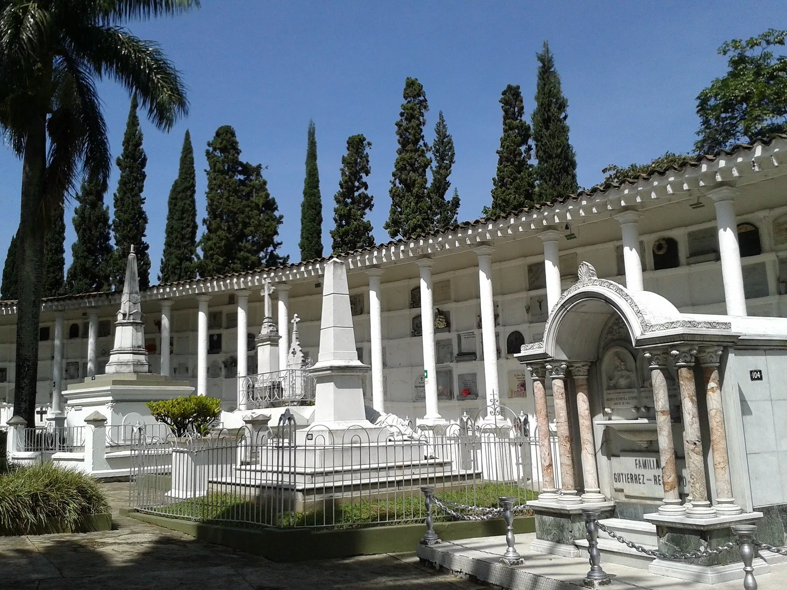 Galería de bóvedas y monumentos funerarios bajo cipreses en el Cementerio San Pedro