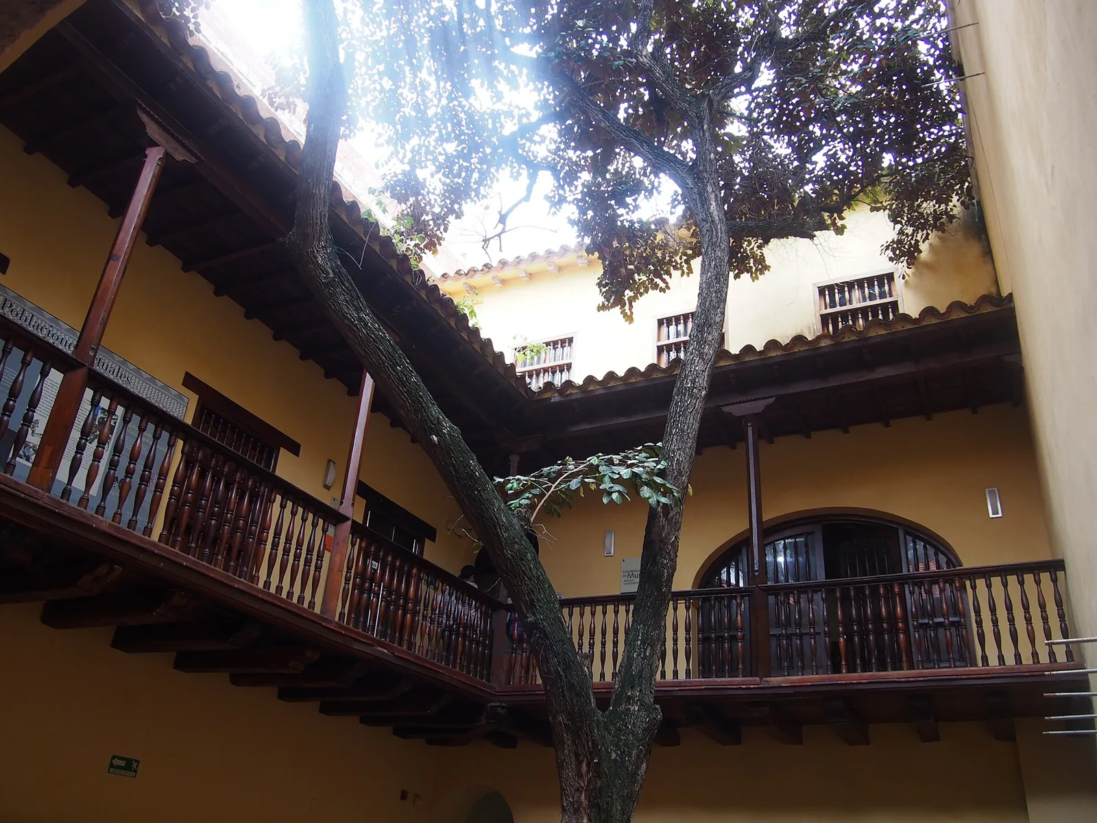 Patio interior del Museo del Oro Zenú con balcones de madera y un árbol