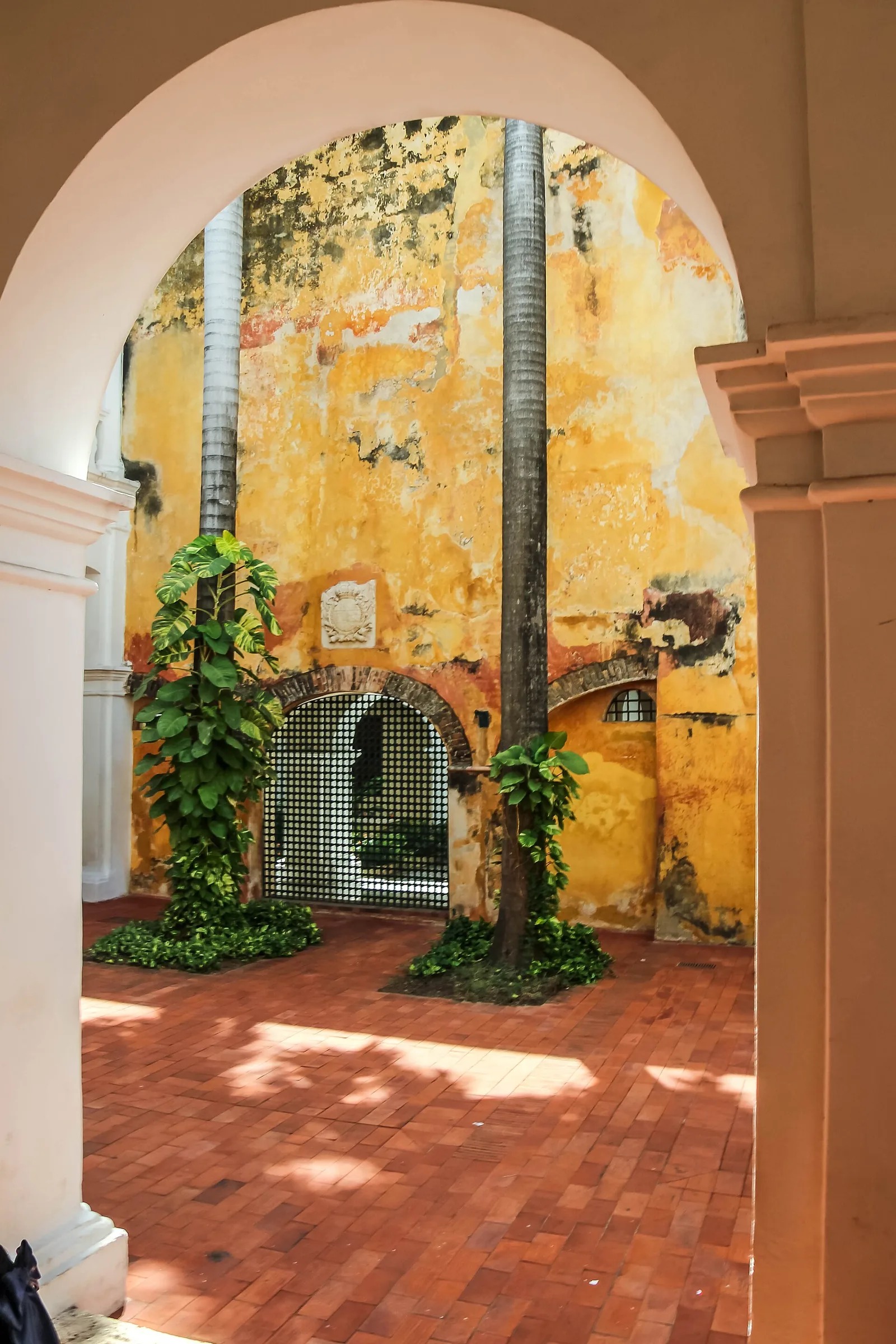 Patio interior del Palacio de la Inquisición, con arco y paredes amarillas