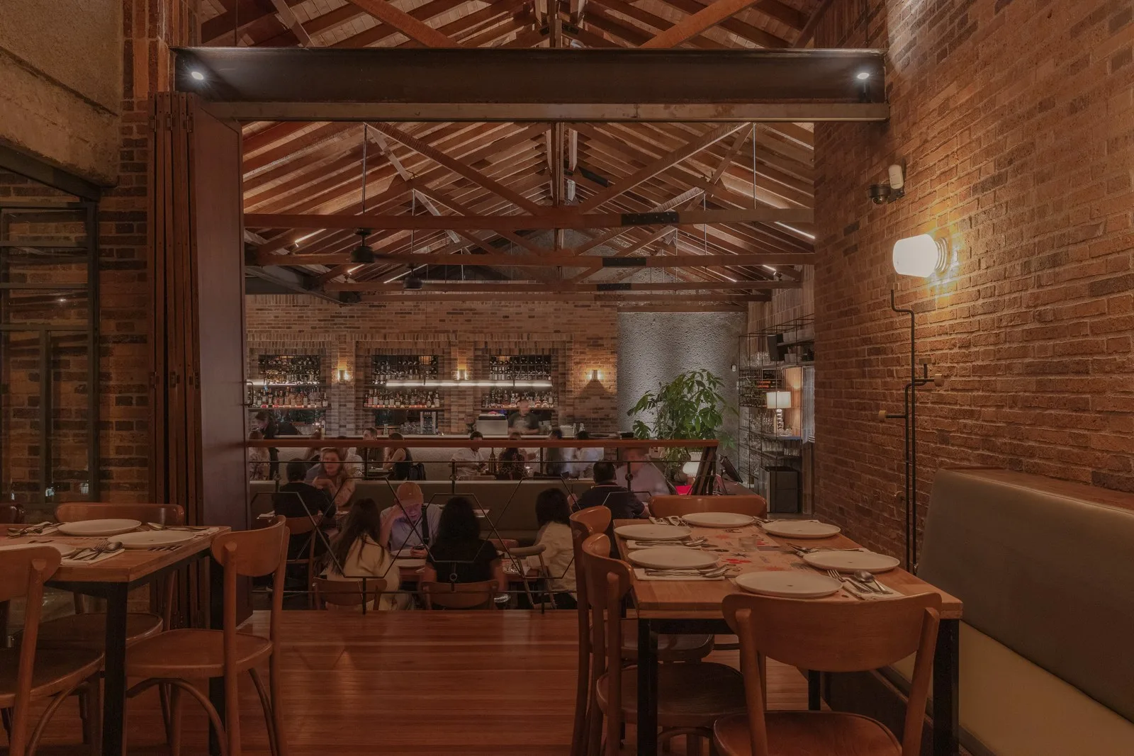 Salón de Ocio con paredes de ladrillo, techo de madera y mesas servidas