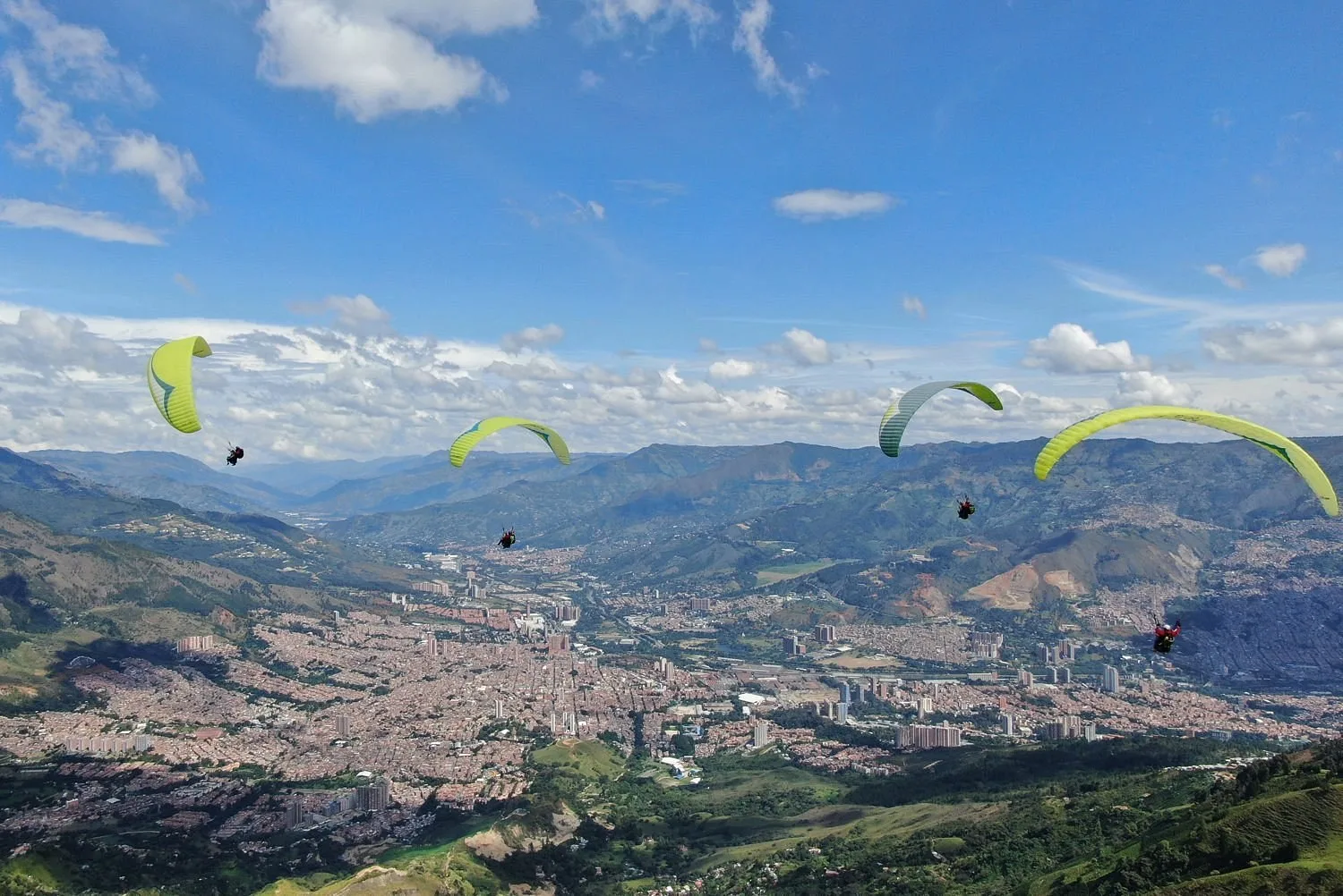 Varios parapentes sobre el valle de Aburrá, saliendo de la zona de vuelo de San Félix