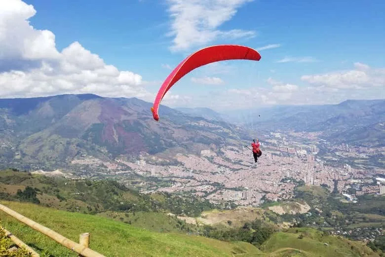 Parapente rojo despegando de la ladera de San Félix con Medellín al fondo
