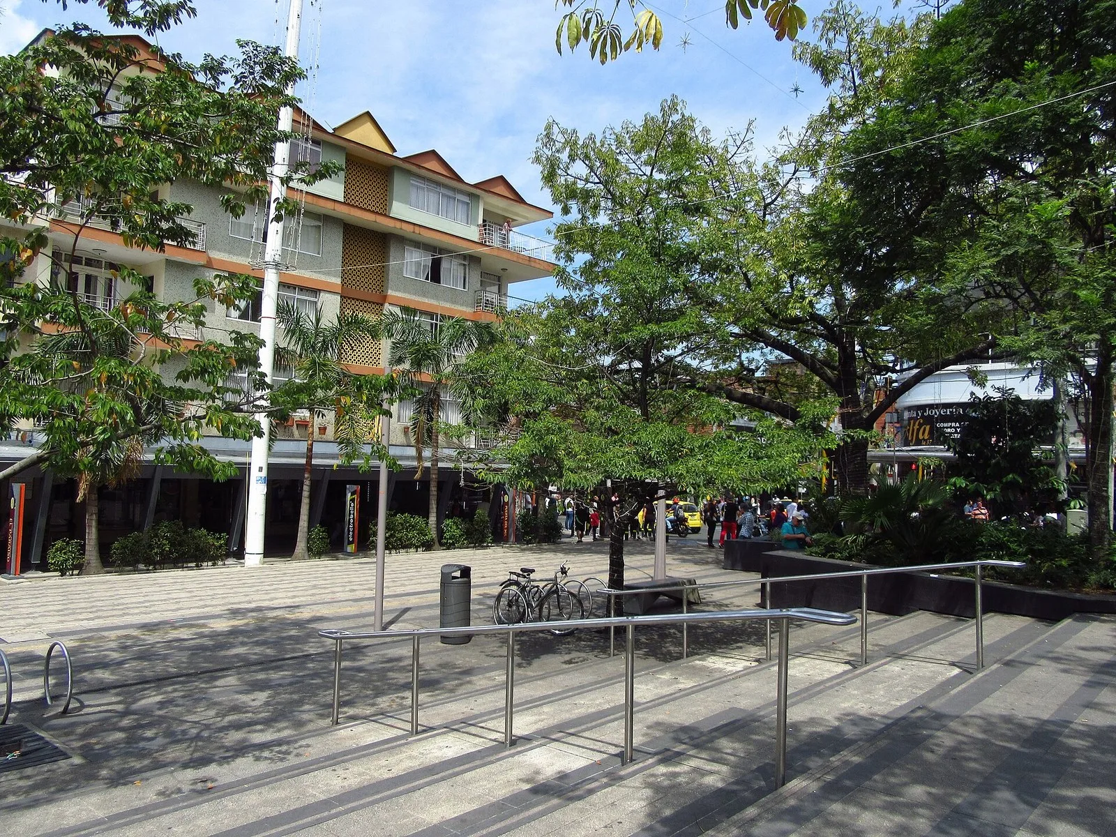 Plazoleta del parque principal de Envigado con árboles, bancas y edificios alrededor
