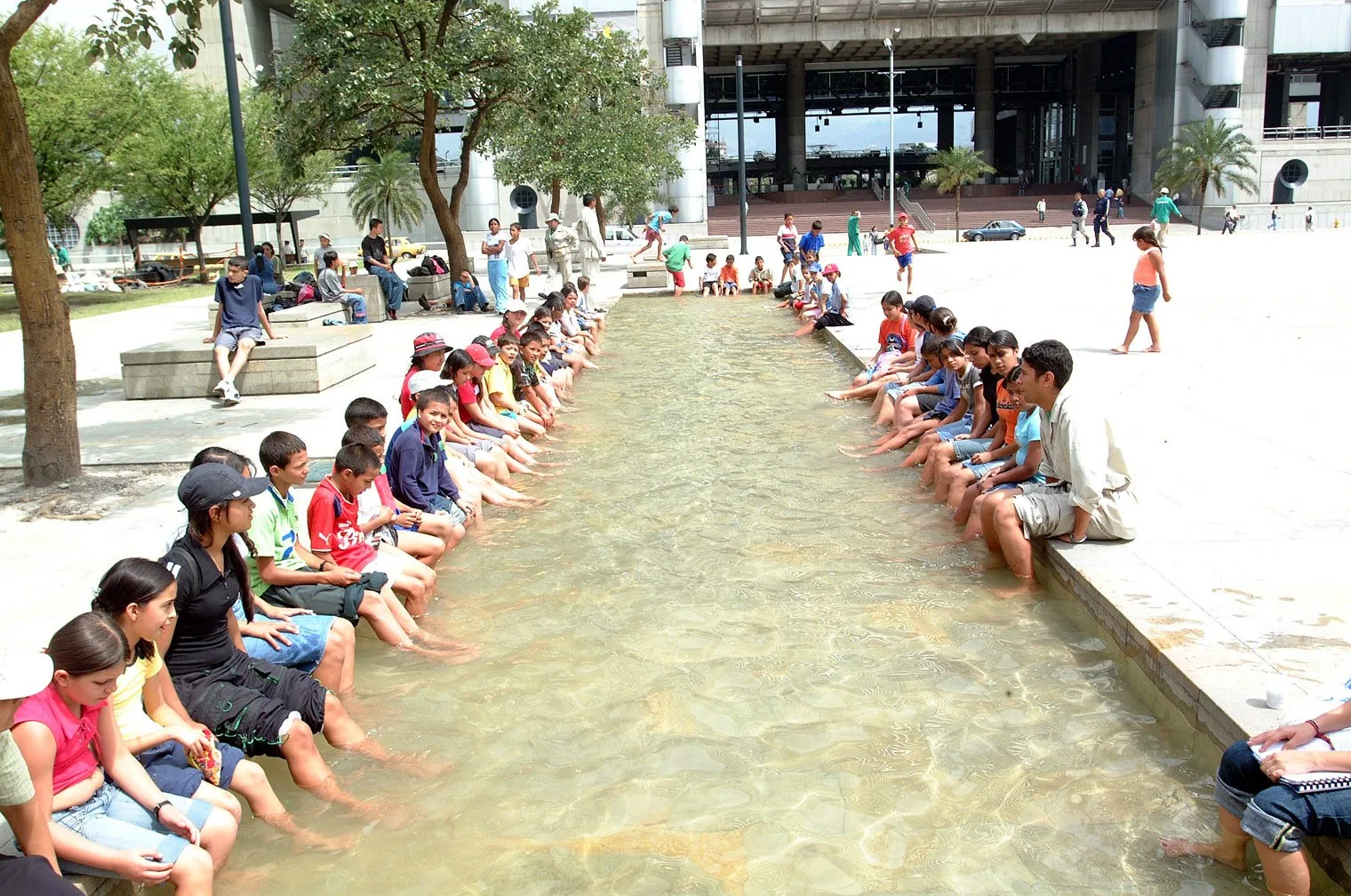 Visitantes con los pies en el canal de agua del Parque de los Pies Descalzos