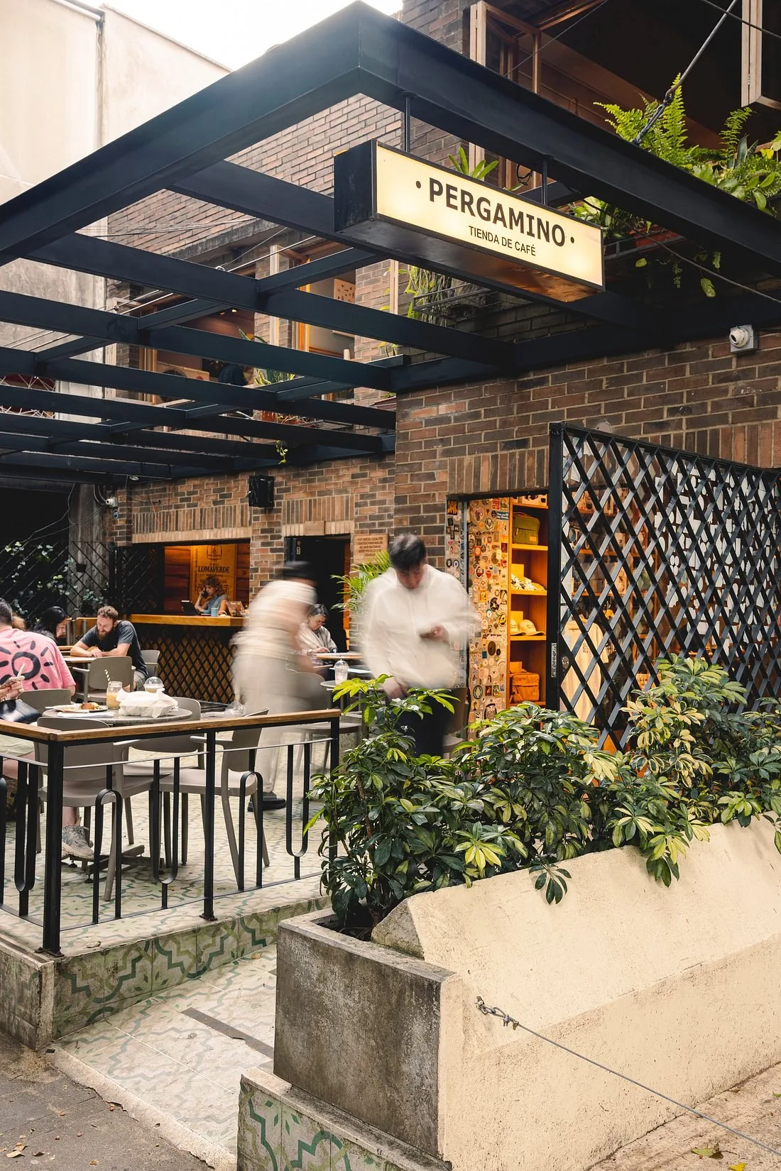 Terraza de Pergamino Café en la Vía Primavera, con muros de ladrillo y plantas