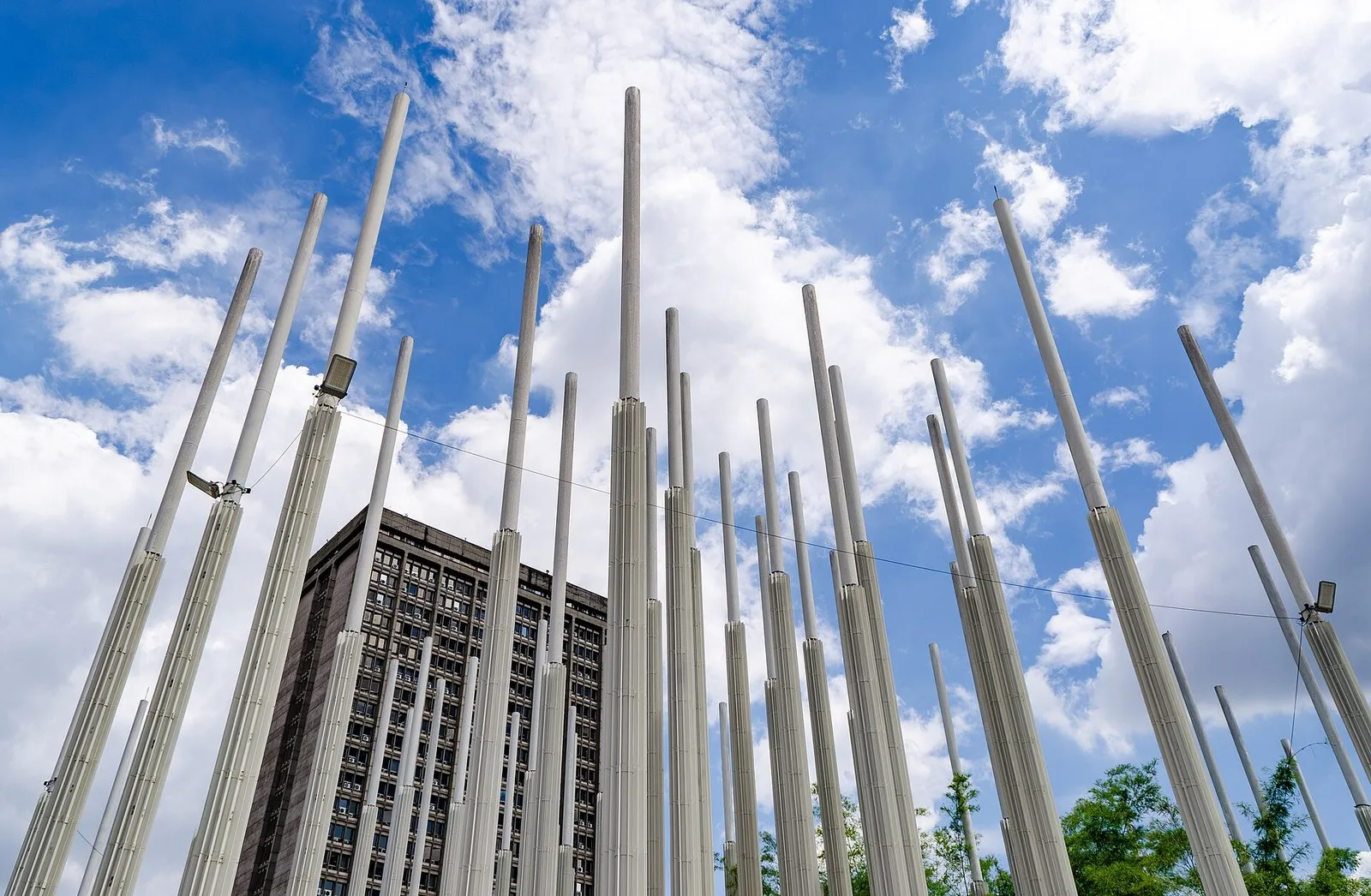 Postes blancos de la Plaza Cisneros vistos desde abajo contra un cielo azul con nubes