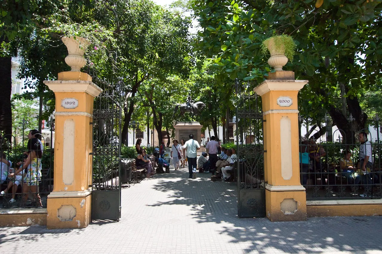 Entrada a la Plaza de Bolívar con sus pilares amarillos y gente a la sombra