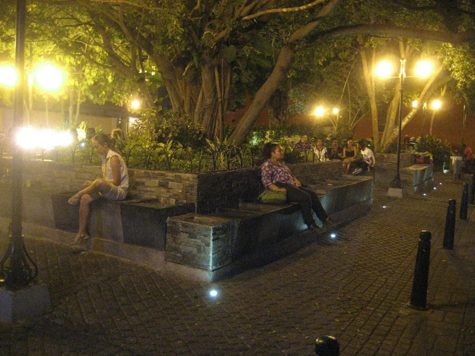 Gente sentada en las bancas iluminadas de la Plaza de San Diego