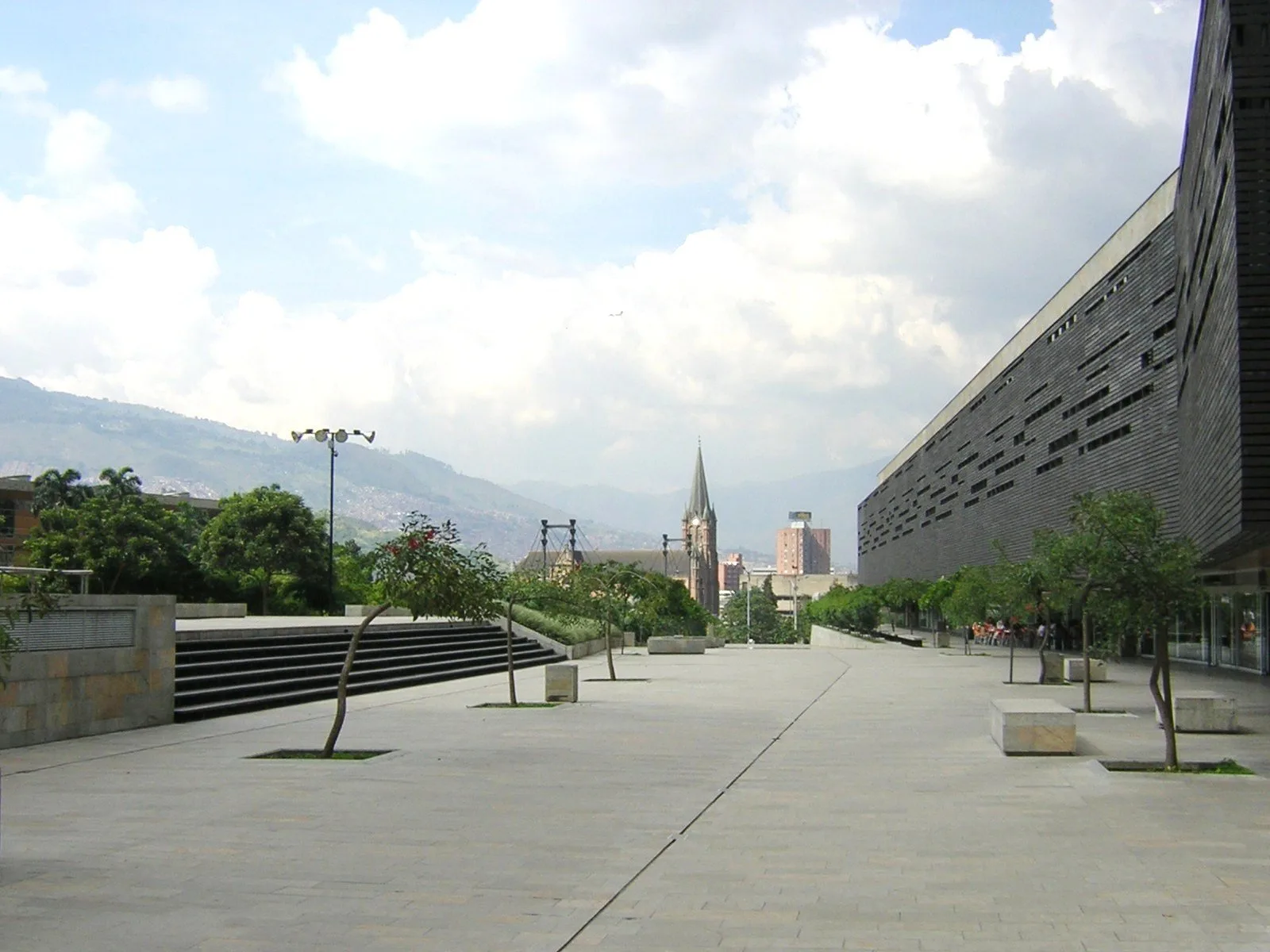 Plazoleta de Plaza Mayor con el edificio de convenciones a la derecha y la torre de la iglesia y las montañas al fondo