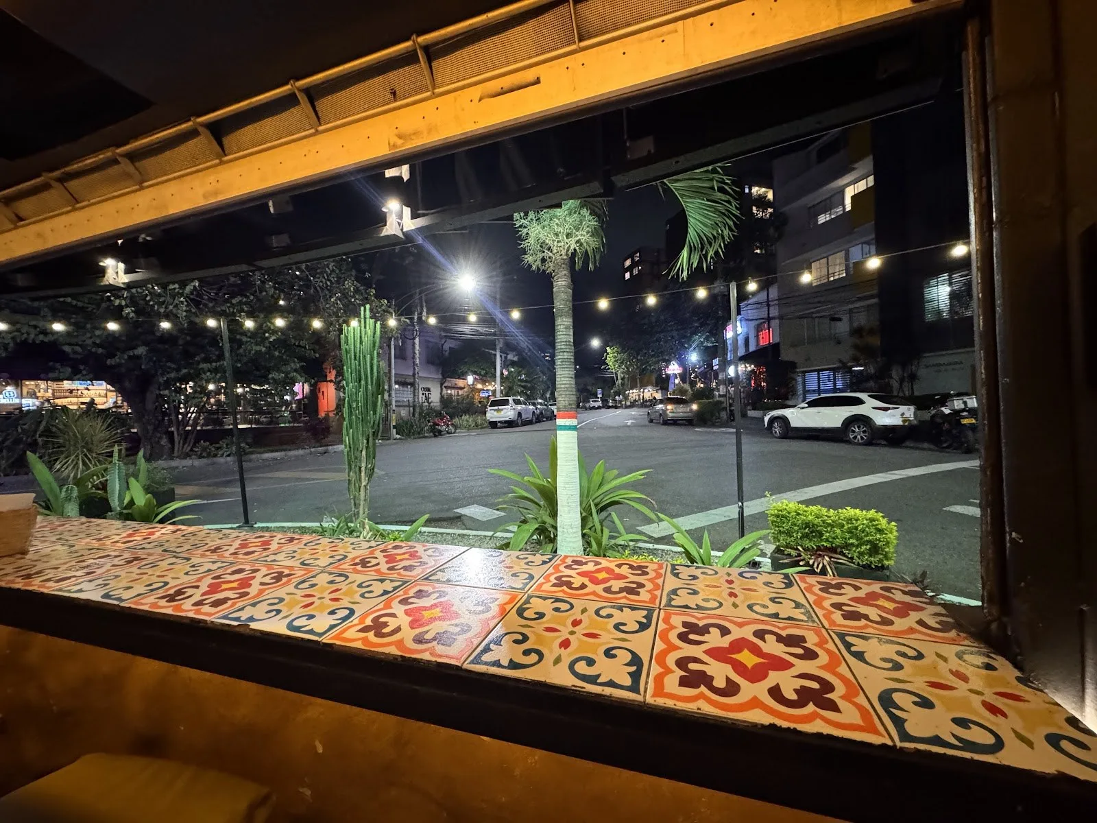 Calle junto al Primer Parque de Laureles de noche, vista desde la ventana de un restaurante