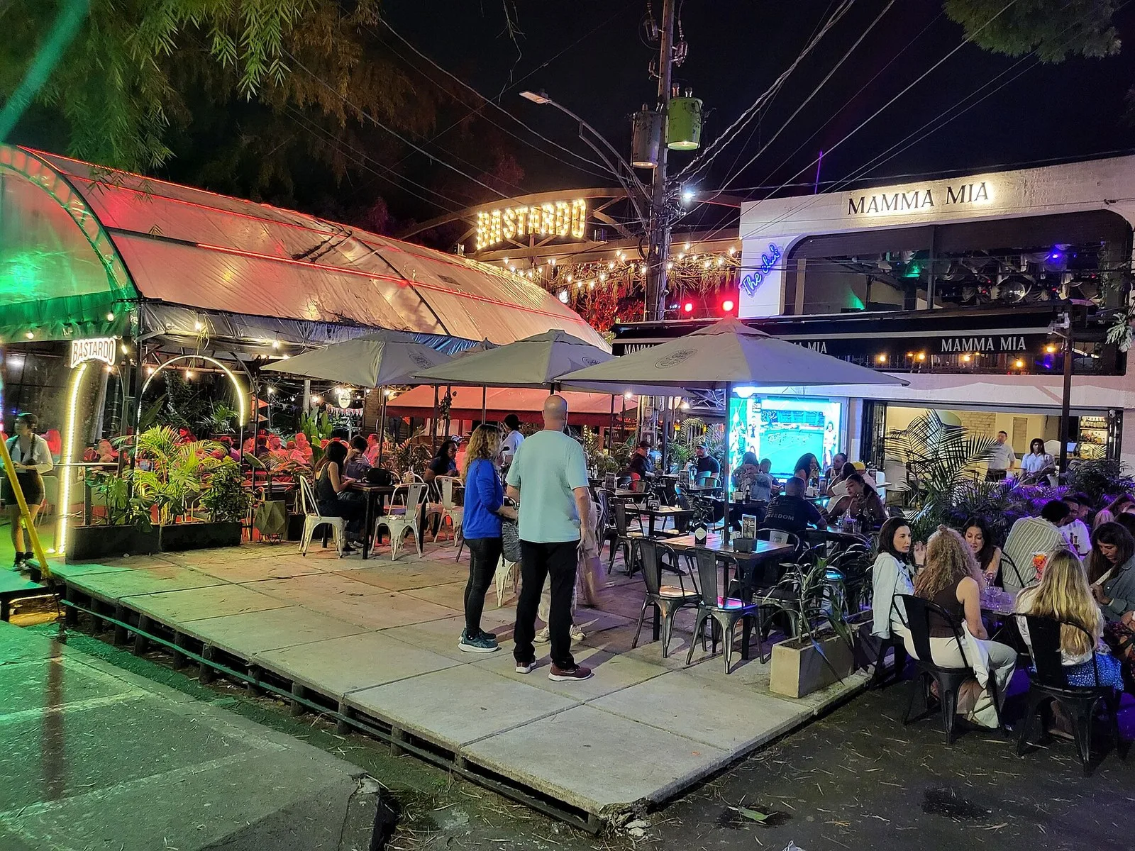 Mesas al aire libre bajo sombrillas en una calle de Provenza de noche