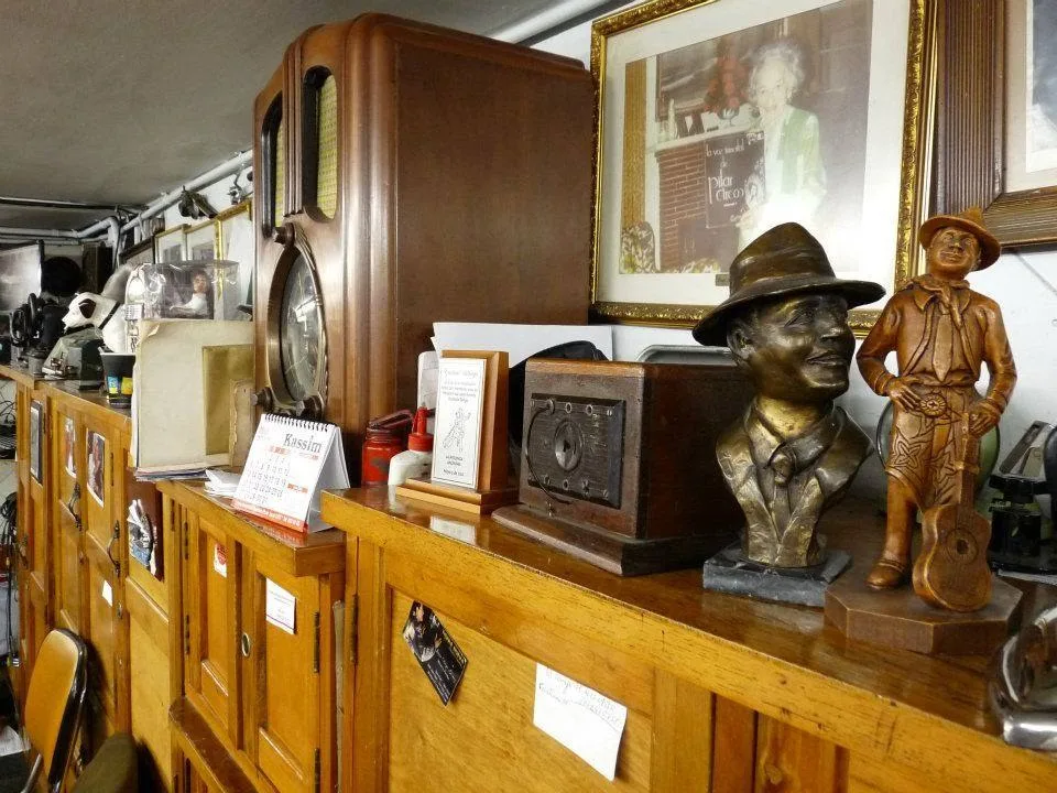 Radios antiguos, bustos y fotos de artistas sobre los muebles de madera del Salón Málaga