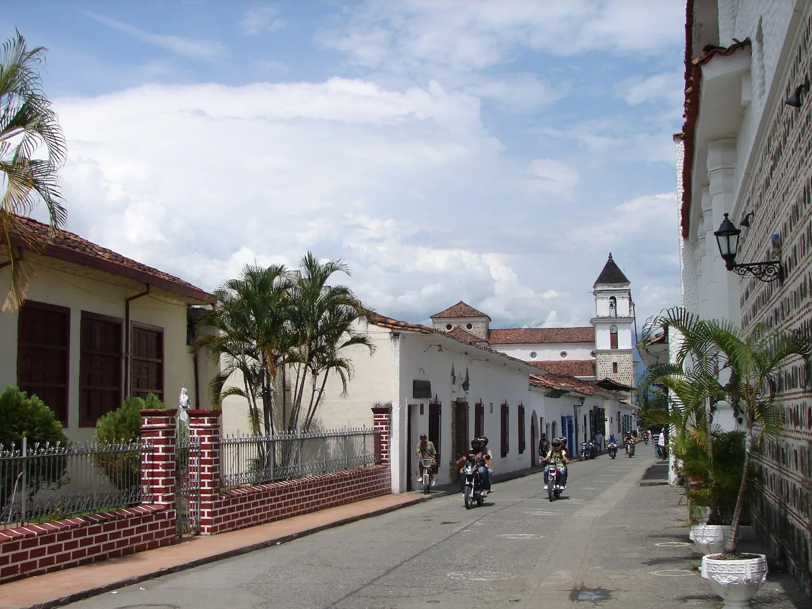 Calle del centro histórico de Santa Fe de Antioquia con casas blancas y una torre de iglesia al fondo